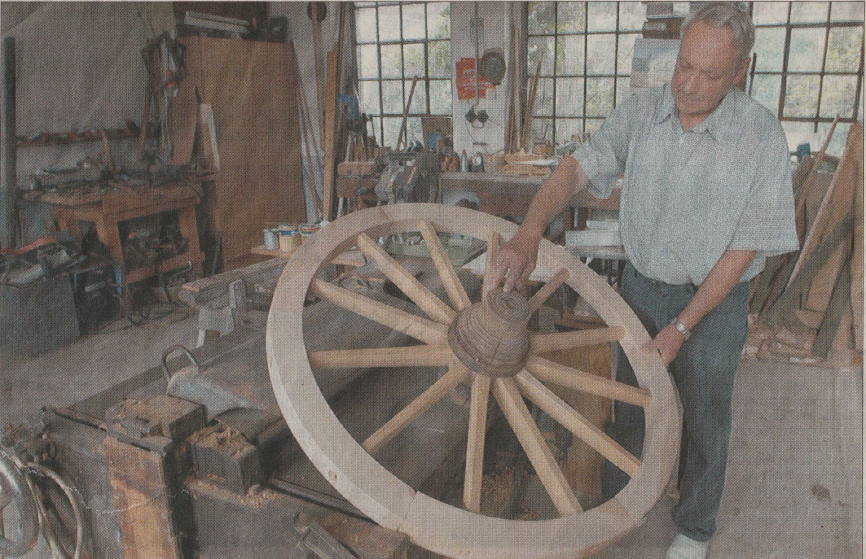 Kurt Heinz Sommer, der den Beruf des Stellmachers gelehrt hat, mit einem vom ihm erstellten Wagenrad.